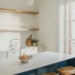 Open shelving kitchen ideas on a budget — two walnut-stained pine shelves with matte black brackets styled with white ceramics and a herb pot