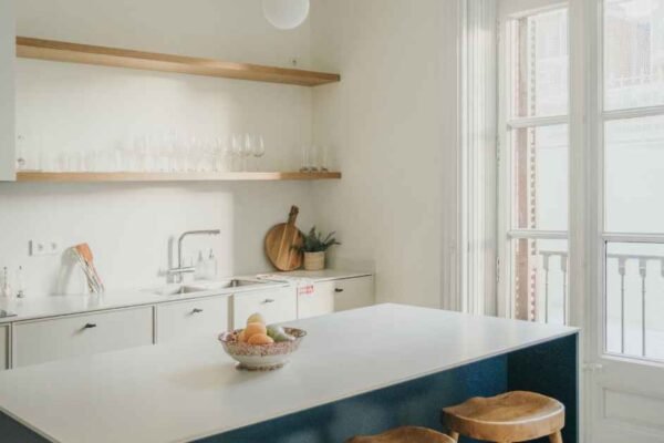 Open shelving kitchen ideas on a budget — two walnut-stained pine shelves with matte black brackets styled with white ceramics and a herb pot
