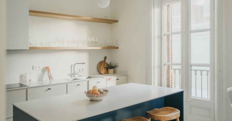 Open shelving kitchen ideas on a budget — two walnut-stained pine shelves with matte black brackets styled with white ceramics and a herb pot